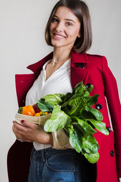 Hermosa mujer sosteniendo la bolsa con verduras orgánicas