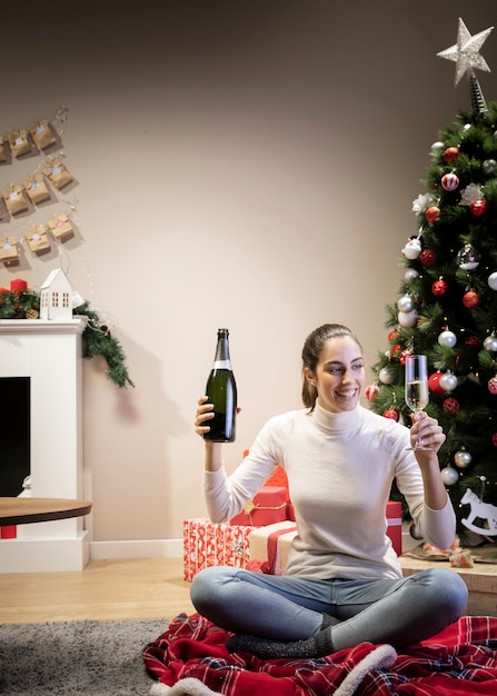 Hermosa mujer sosteniendo una botella y una copa de champán