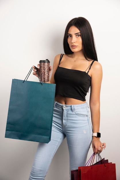 Hermosa mujer sosteniendo café y bolsas de compras. Foto de alta calidad