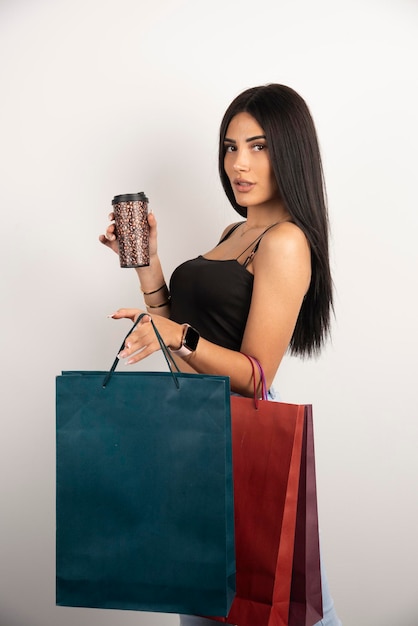 Hermosa mujer sosteniendo café y bolsas de compras. Foto de alta calidad