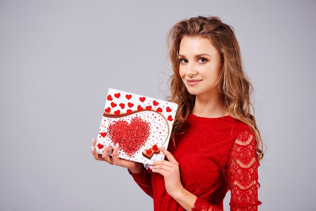 Hermosa mujer sosteniendo una caja de bombones en forma de corazón
