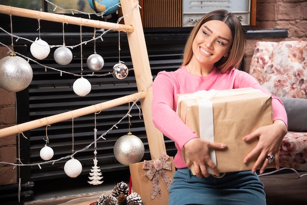 Hermosa mujer sosteniendo caja de regalo en casa