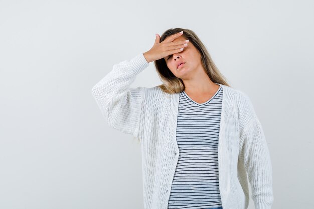 Hermosa mujer sosteniendo la mano en la cabeza con chaqueta, camiseta y aspecto cansado. vista frontal.