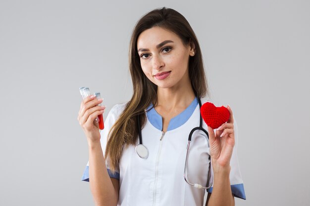 Hermosa mujer sosteniendo una muestra de sangre y corazón de felpa