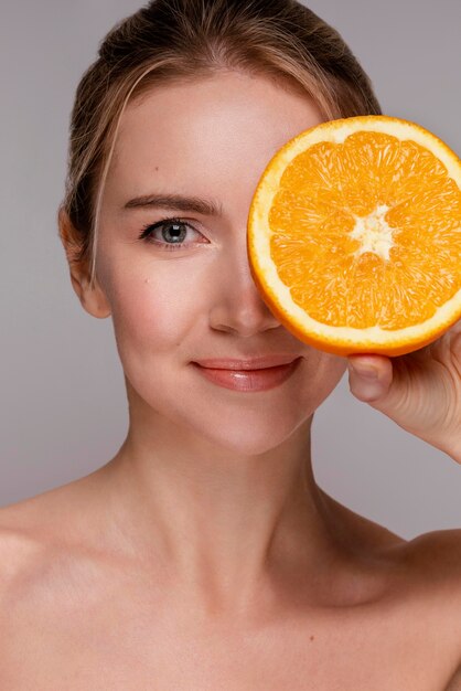 Hermosa mujer sosteniendo naranja a la mitad