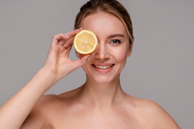 Hermosa mujer sosteniendo naranja a la mitad