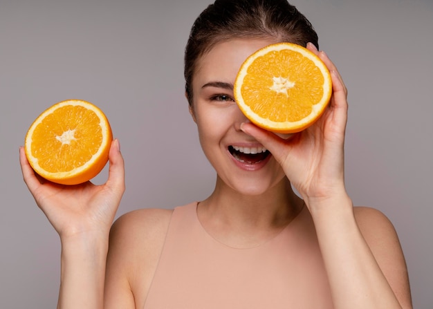 Hermosa mujer sosteniendo naranja a la mitad