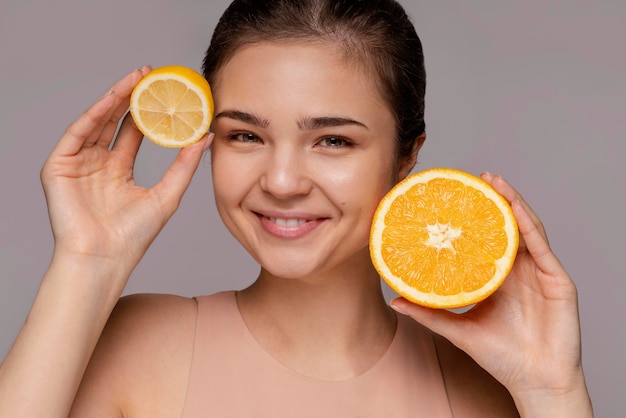 Hermosa mujer sosteniendo naranja a la mitad