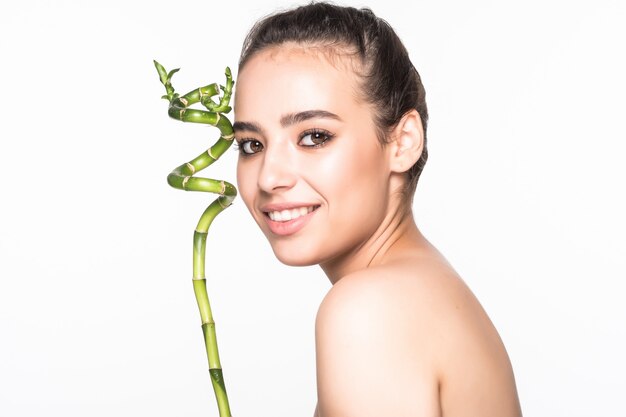 Hermosa mujer sosteniendo un palo de bambú en una pared blanca