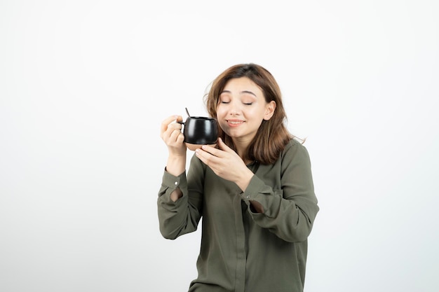 Hermosa mujer sosteniendo una taza de café y de pie sobre blanco. foto de alta calidad