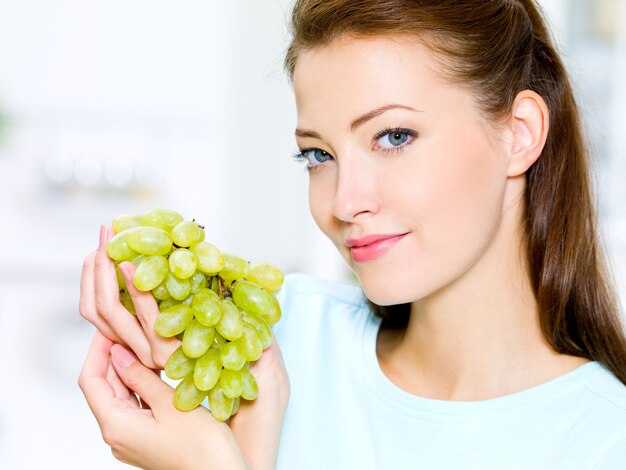 Hermosa mujer sostiene uvas - en el interior