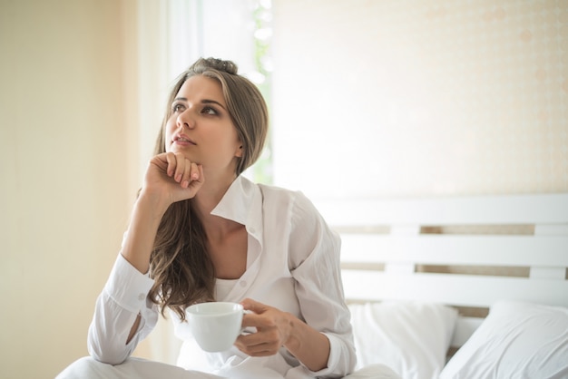 Hermosa mujer en su habitación tomando café por la mañana