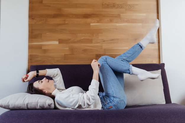 Hermosa mujer en suéter blanco y blue jeans divertirse en mal durante el día