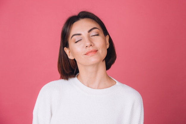 Hermosa mujer en suéter blanco casual, aislado permanente cara tranquila ojos cerrados sonrisa linda