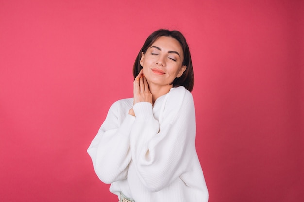 Hermosa mujer en suéter blanco casual, concepto de amor, tomados de la mano cruzados abrazándose a sí misma con los ojos cerrados