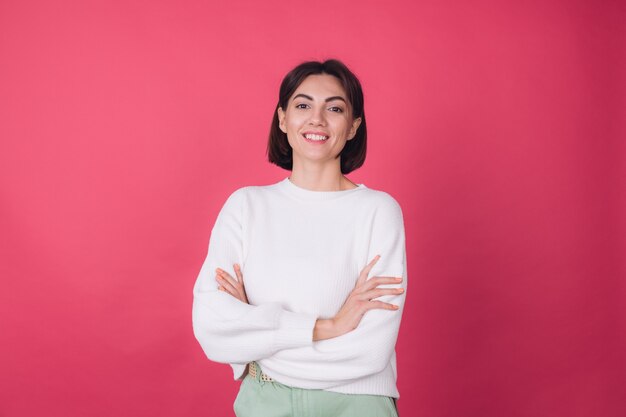 Hermosa mujer en suéter blanco casual, con sonrisa de manos cruzadas