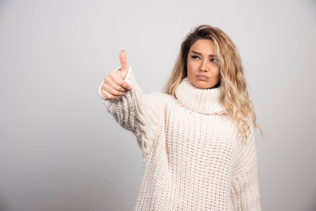 Hermosa mujer en suéter de invierno dando pulgares.