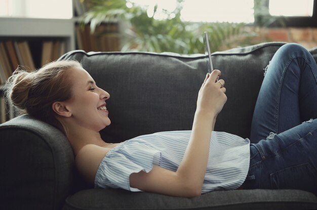 Hermosa mujer con tableta digital, tumbado en el sofá