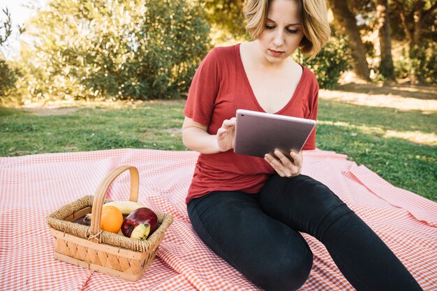 Hermosa mujer con tableta en picnic