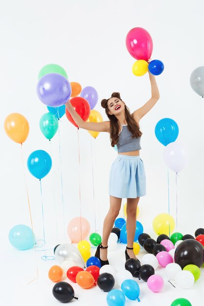 Hermosa mujer con tacones parece feliz jugando con globos