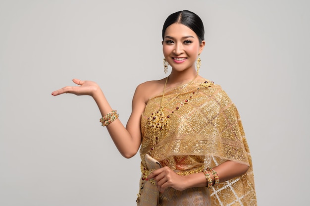 Hermosa mujer tailandesa usa ropa tailandesa y abre su mano a la derecha