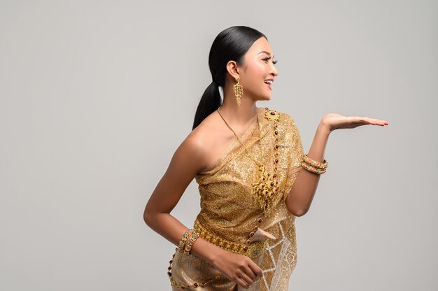 Hermosa mujer tailandesa usa ropa tailandesa y abre su mano a la izquierda