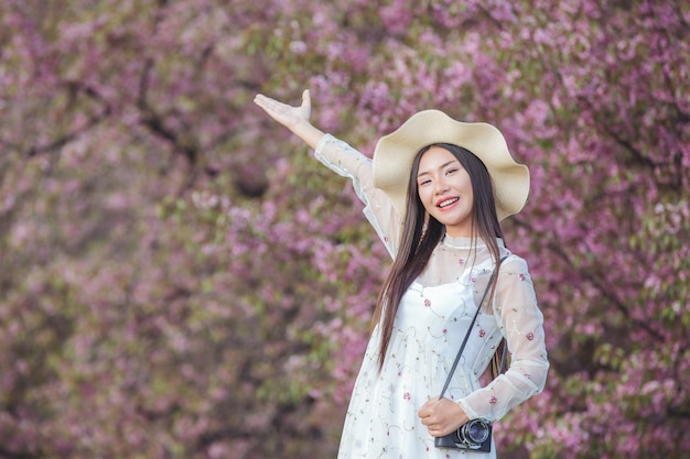 Una hermosa mujer toma una foto con una cámara de cine en el jardín de flores de Sakura.