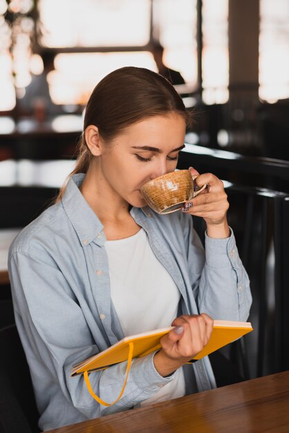 Hermosa mujer tomando café y sosteniendo un cuaderno