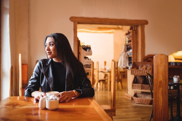 Hermosa mujer tomando una taza de café en la cafetería