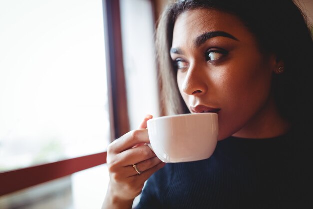 Hermosa mujer tomando una taza de café en la cafetería