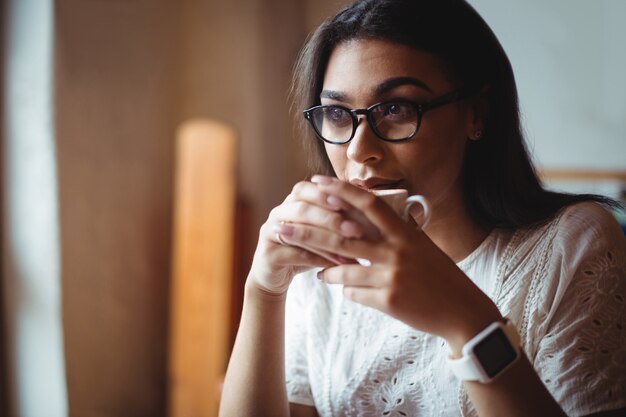 Hermosa mujer tomando una taza de café en la cafetería