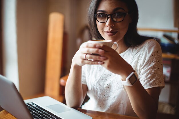 Hermosa mujer tomando una taza de café en la cafetería