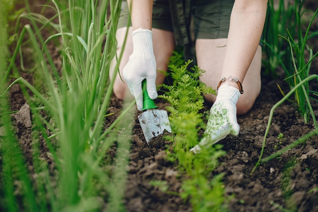 Hermosa mujer trabaja en un jardín cerca de la casa