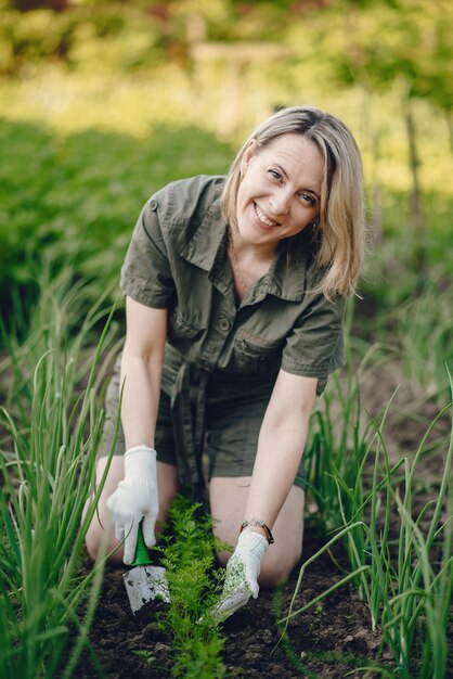 Hermosa mujer trabaja en un jardín cerca de la casa