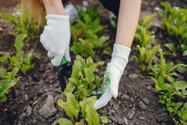 Hermosa mujer trabaja en un jardín cerca de la casa