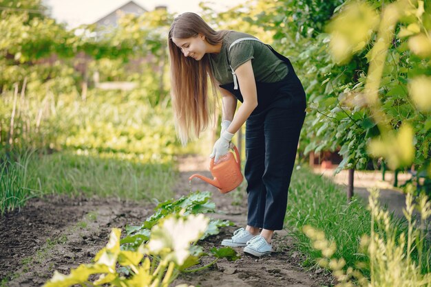 Hermosa mujer trabaja en un jardín cerca de la casa