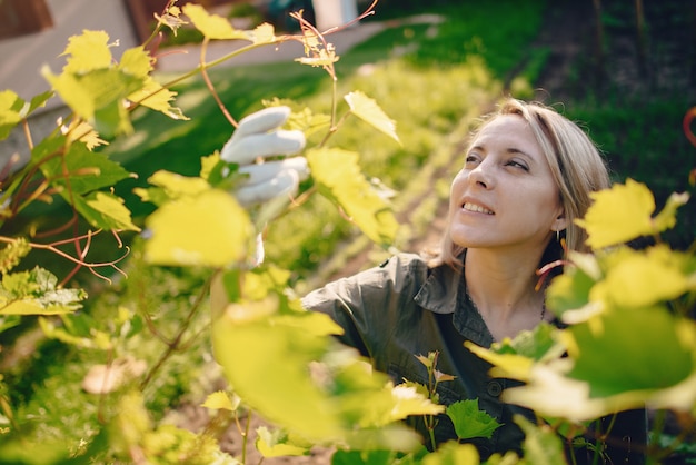 Hermosa mujer trabaja en un jardín cerca de la casa