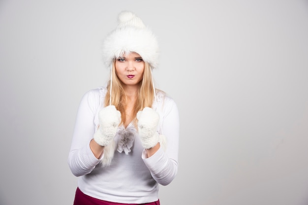 Hermosa mujer en traje de invierno jugando con sombrero.