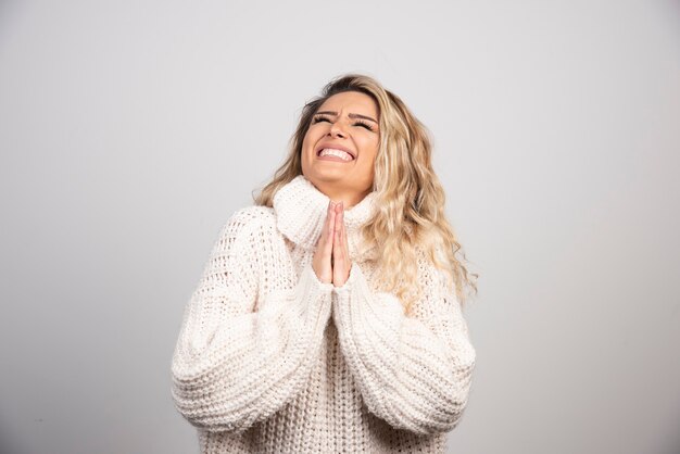 Hermosa mujer en traje de invierno rezando por la felicidad.