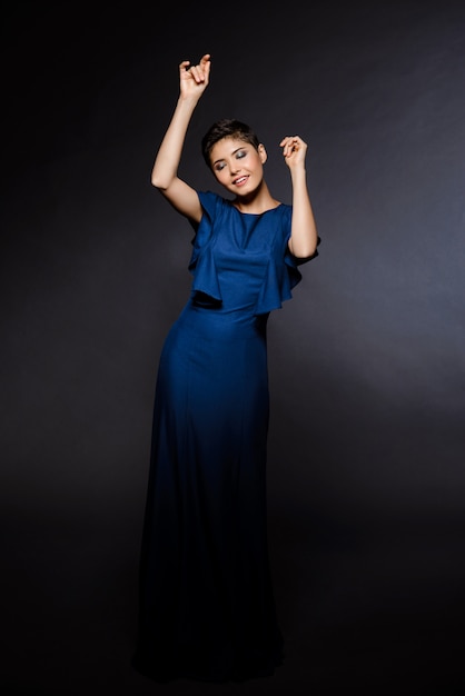 Hermosa mujer en traje de noche bailando, sonriendo