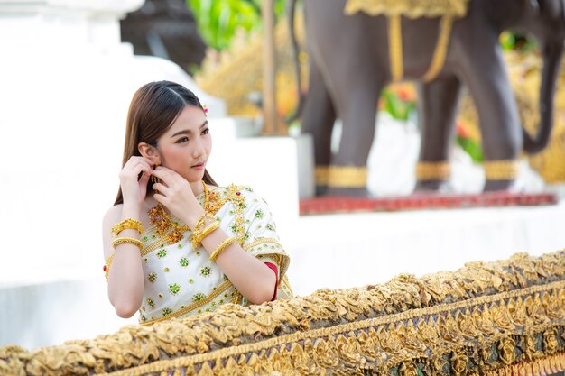 Hermosa mujer en traje tradicional tailandés sonriendo y de pie en el templo
