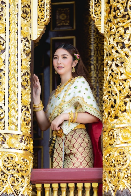 Hermosa mujer en traje tradicional tailandés sonriendo y de pie en el templo