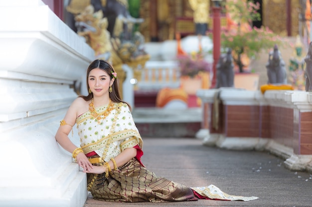 Hermosa mujer en traje tradicional tailandés sonriendo y de pie en el templo