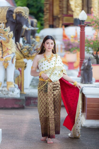 Hermosa mujer en traje tradicional tailandés sonriendo y de pie en el templo