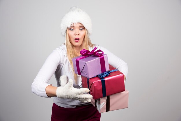 Hermosa mujer tratando de sostener los regalos de Navidad.