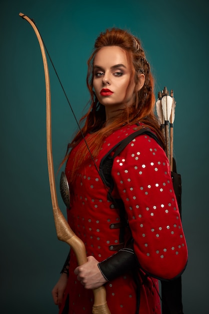 Hermosa mujer en túnica medieval con arco y flechas.