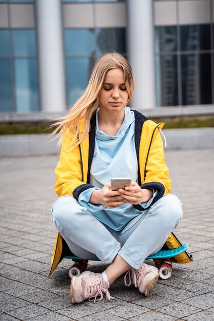 Hermosa mujer usa teléfono inteligente y se sienta en patineta