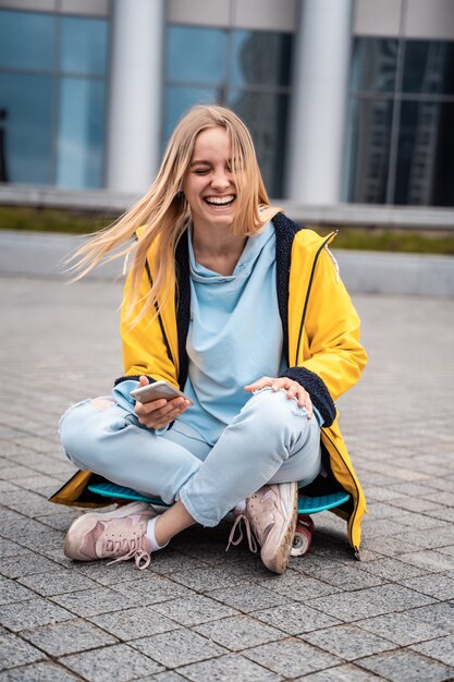 Hermosa mujer usa teléfono inteligente y se sienta en patineta