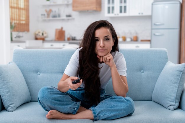 Hermosa mujer usando el control remoto para cambiar los canales