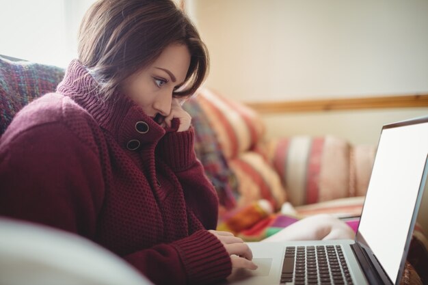 Hermosa mujer usando laptop en sofá